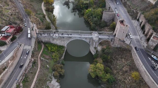 Aerial view of the Puente de San Martin bridge over the Tagus River, its stone arches reflecting in the waters, Toledo, Castile-La Mancha, Spain.