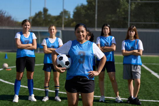 Young women soccer team standing confidently on field