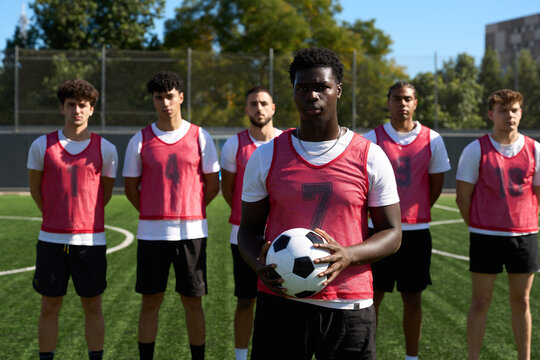 Diverse soccer team posing on green grass field