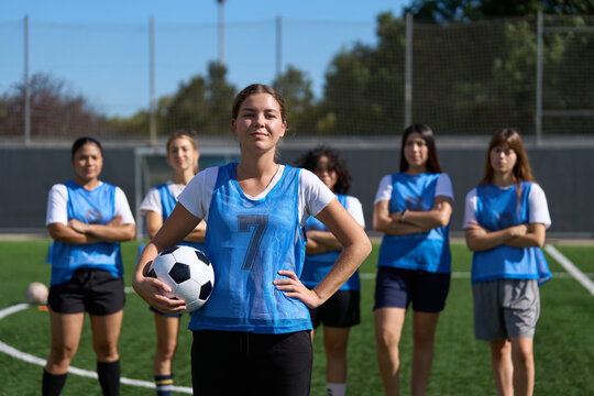 Young woman soccer player holding ball with team