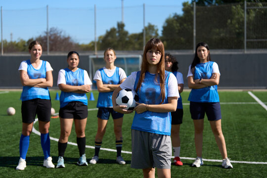 Women's soccer team standing on pitch with player holding ball