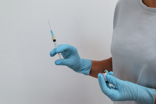 Nurse preparing an injection. Hands in gloves holding a syringe and a glass ampoule.