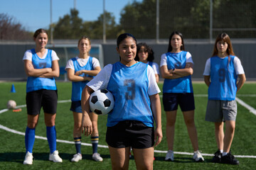Young women soccer team standing united on field