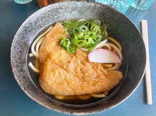 Bowl of udon noodles with fried tofu and green onions