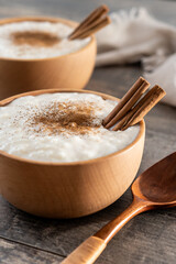 Rice pudding with cinnamon in wooden bowl on wooden table