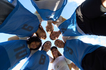 Women's soccer team huddling, showing unity and teamwork
