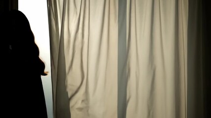 Silhouette of a person standing behind a curtain in a dark room. Mysterious figure walks away from the window light. Concept of loneliness and departure - Powered by Adobe