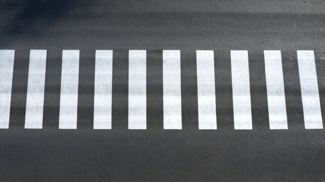 Overhead view of white pedestrian crossing stripes on dark asphalt road surface - Powered by Adobe