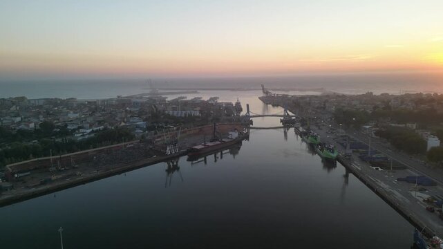 Aerial view of the harbor featuring ships, cranes, and a bridge over the water, reflecting the sunrise in Leca da Palmeira, Porto District, Portugal.
