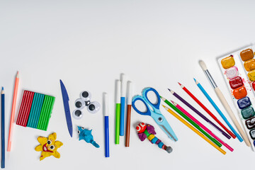 Stationery on a white background with a place for text, colored cardboard, paints, figures made of plasticine, the concept of a school, kindergarten and DIY