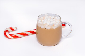 Christmas scene flat lay with knitted mittens, candy cane and mug of hot drink topped with marshmallows on a white background. Perfect for a Christmas background