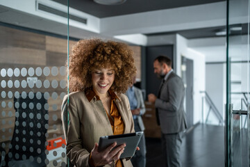 Businesswoman smiling while using digital tablet in modern office