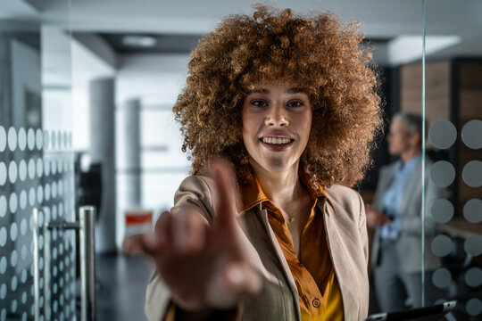 Confident businesswoman pointing finger at interactive screen in office