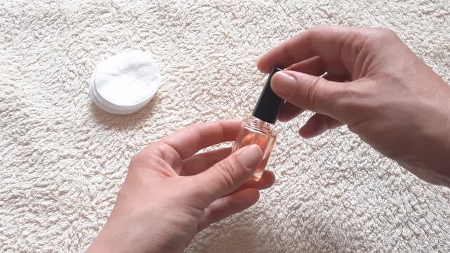 Manicurist closing a nail and cuticle oil bottle after a manicure procedure. Close-up female hands twisting and closing nail care oil bottle after manicure in a nail salon, spa studio, or bathroom