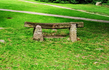 Grand banc de bois et pierre sur une pelouse dans un parc.