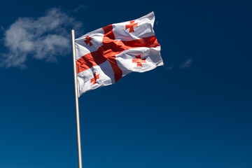 National Flag Of Georgia Waving Against Clear Blue Sky