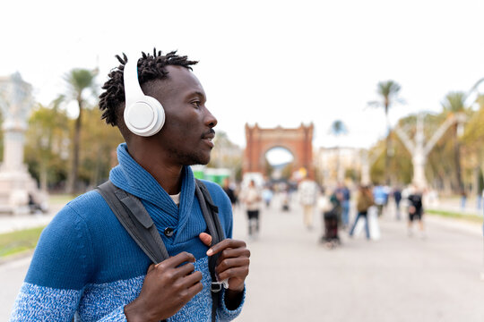 African American man traveling, wearing headphones, listening to music, and enjoying the urban street atmosphere