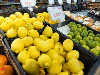Fresh yellow lemons displayed in crates at a supermarket produce section, showing vibrant citrus fruits arranged for sale in a grocery store environment.