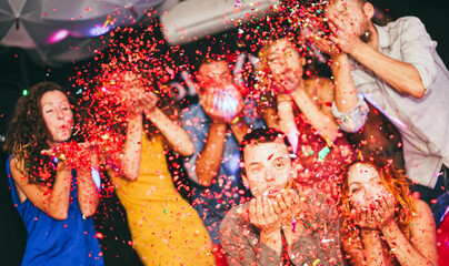 Young friends having party throwing confetti - Young people celebrating on weekend night -...