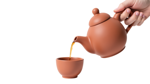 Hand pours tea from clay teapot into matching cup, showcasing warm and inviting moment of tea preparation