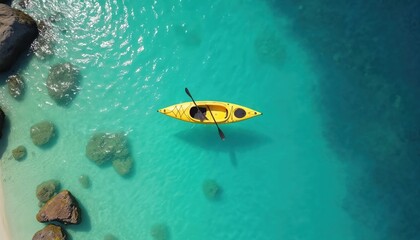Yellow kayak floats on clear turquoise ocean water. Sunlit scene shows rocks near sandy shore and deep blue sea. Peaceful water sport adventure.