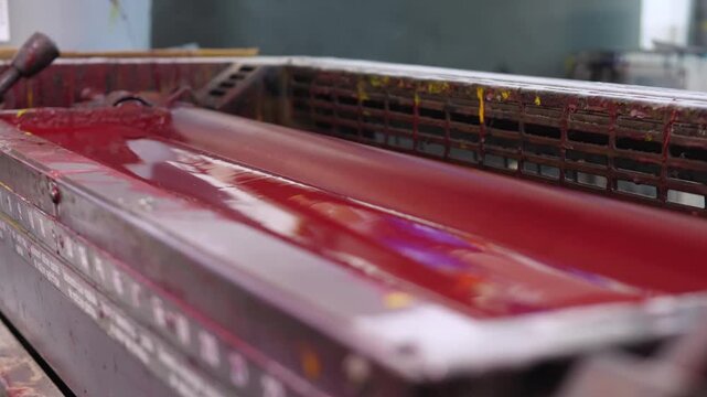 Red ink rollers inside offset printing press spreading vivid pigment