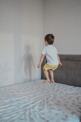 Young Boy Jumping on a Bed with Shadow on the Wall