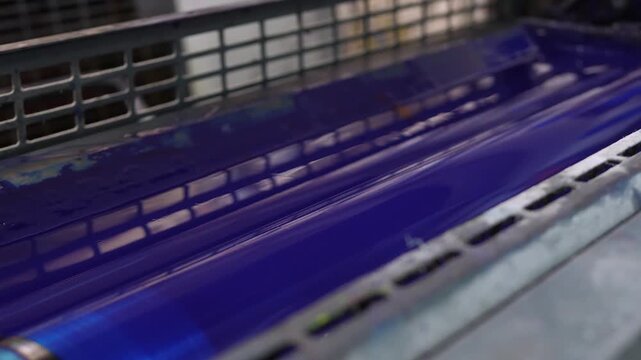 Blue ink rollers operating inside offset printing press mechanism