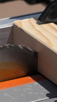 Side close view of carpenter cutting wood with table saw