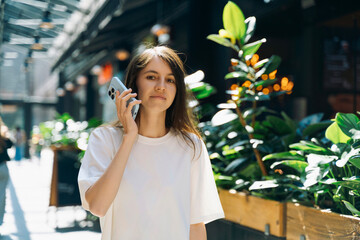 Young woman holding smartphone while walking outdoors