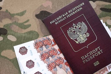 Russian passport with money on multicam camouflage fabric close up. Concept of russian army funds...