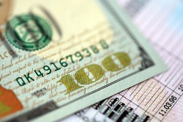 Hundred dollar bill on US driver license close up. Concept of driving lessons or automobile taxpaying