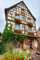 Dekoriertes Fachwerkhaus mit verzierten Fenstern und Blumen in der Altstadt von Kaysersberg, Frankreich