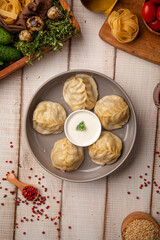 Steamed manty dumplings with meat filling served with creamy sauce on a rustic wooden table
