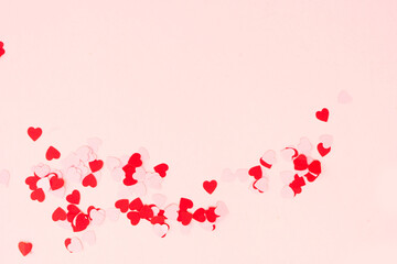 Valentines day festive background with scattered hearts over pink background, border copy space