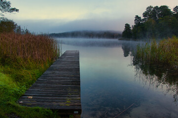 Mglisty poranek nad jeziorem z drewnianym pomostem wychodzącym na spokojną wodę. Drawieński Park Narodowy – Jezioro Głuche Duże. © Pol Badger