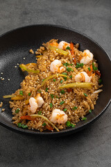 Savory fried rice cooked with shrimp vegetables sesame seeds and herbs served on dark plate