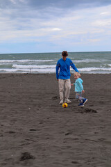 Two brothers play football and have fun on black sand beach in Kobuleti, Georgia