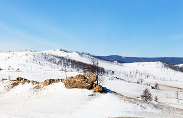 Winter travel across Tazheran steppe to Lake Baikal. View of snow-capped hills and bizarre weathered rocks. Tourists love to visit this unusual place called Valley of Stone Spirits in nature park