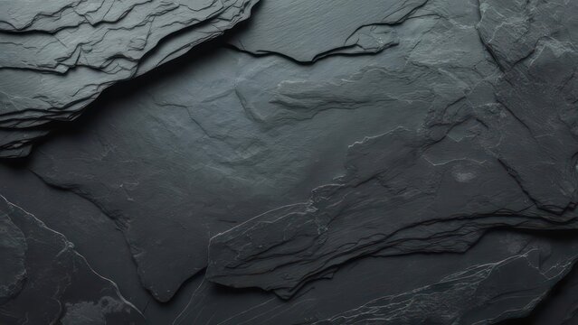 Close-up of overlapping dark gray slate tiles. Textural, natural stone surface