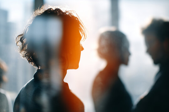 Faceless silhouettes brainstorming behind frosted glass in a coworking studio, subtle defocus, creative energy, with copy space