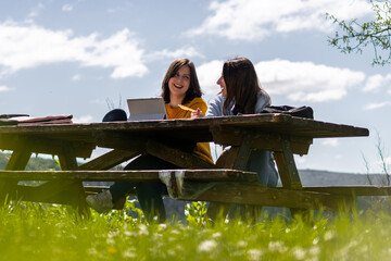 University students studying outdoors with laptop and books on a picnic table
