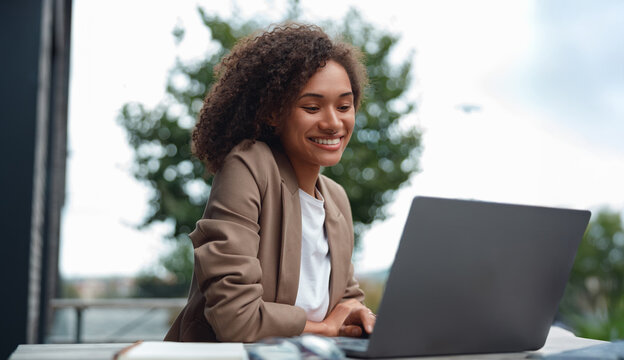 black developer coding on laptop outdoors with coffee nearby, focused expression while typing lines of code,