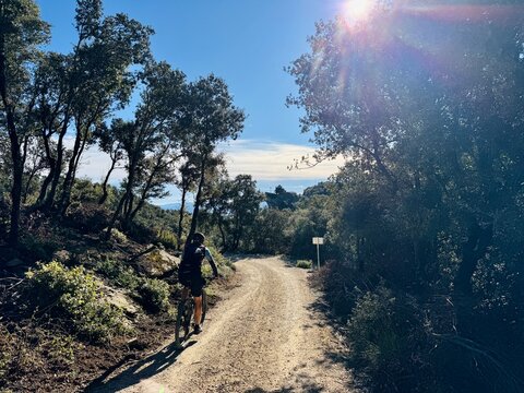 Cyclist approaching Rocacorba sanctuary on rural path on sunny day