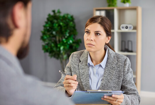 Job interview process with female recruiter and candidate, advisor meeting client for business documents review in office. Serious young woman listening to man sitting at desk on hiring consultation - Powered by Adobe