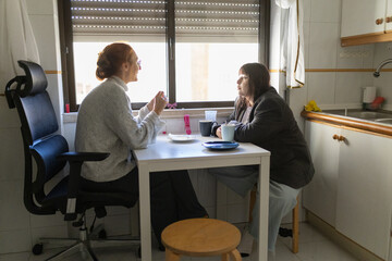 Women talking at kitchen table sharing private conversation