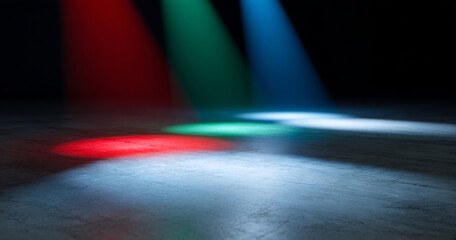 Colorful stage spotlights casting red, green, and blue light beams on a dark textured floor with dramatic shadows and empty space
