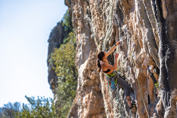 Woman rock climbing. Strong girl climbing a rock. Extreme hobby. Overcoming a difficult rock...
