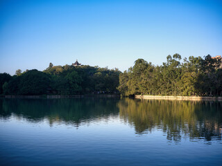 Obraz premium Tranquil Lake with Tree and Pavilion Reflections