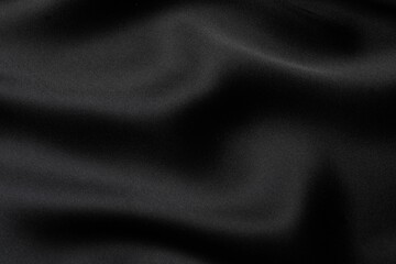 Black silk satin. Shiny smooth fabric. Soft folds. Luxury background with space for design. Flat table, top view